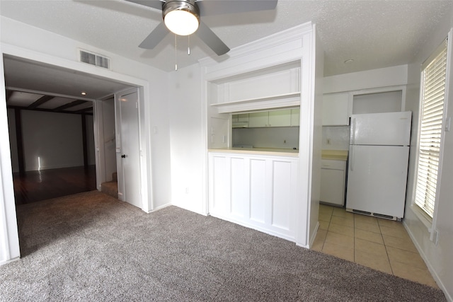 carpeted spare room featuring a healthy amount of sunlight, ceiling fan, and a textured ceiling