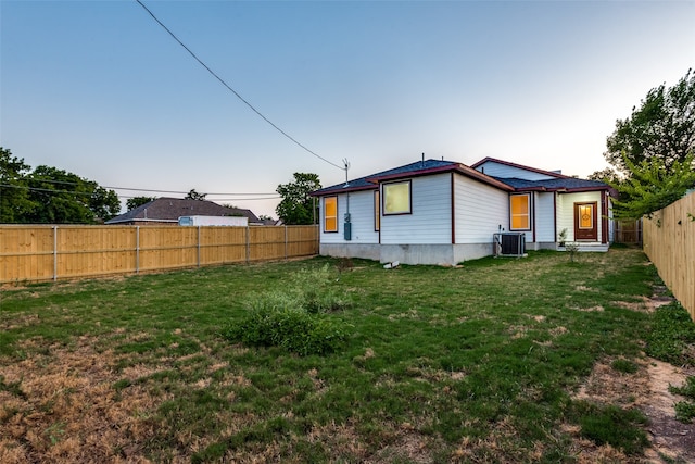 rear view of house featuring cooling unit and a yard