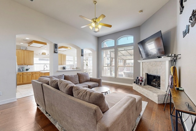 living room featuring light hardwood / wood-style flooring, sink, plenty of natural light, and a brick fireplace