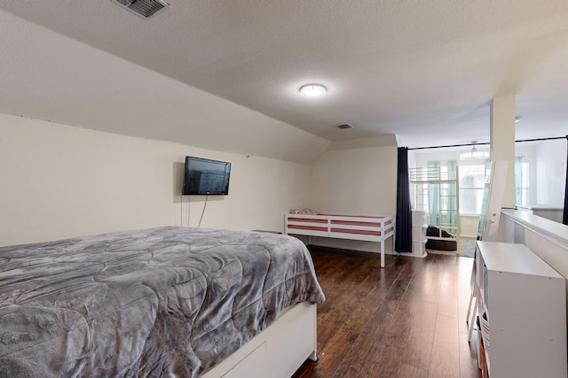 bedroom with dark hardwood / wood-style floors, a textured ceiling, and vaulted ceiling