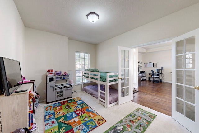 bedroom with french doors, a textured ceiling, and hardwood / wood-style flooring