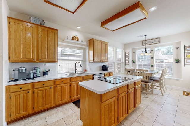 kitchen featuring sink, a center island, hanging light fixtures, and a healthy amount of sunlight