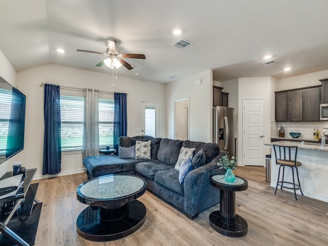 living room with light hardwood / wood-style flooring, sink, ceiling fan, and vaulted ceiling