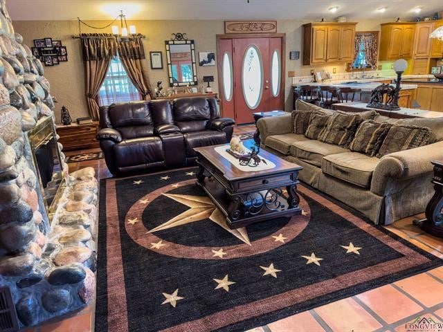 living room featuring a chandelier and a stone fireplace