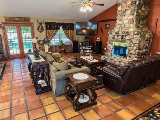 living room with ceiling fan, a fireplace, vaulted ceiling, and tile floors