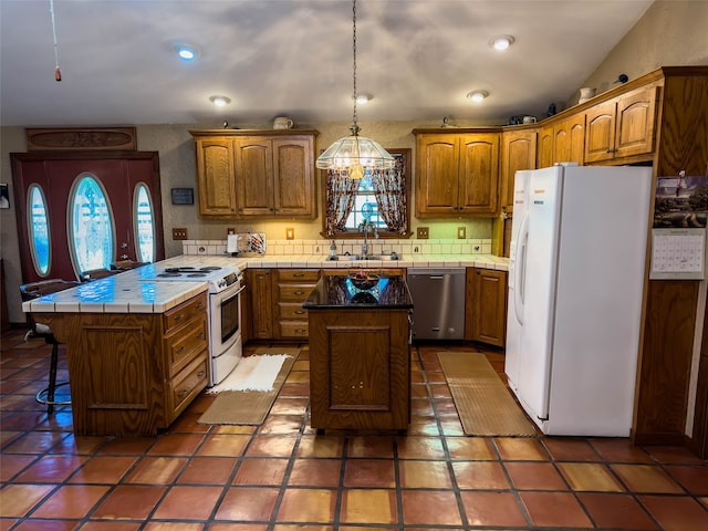 kitchen with pendant lighting, white appliances, tile floors, sink, and a kitchen island