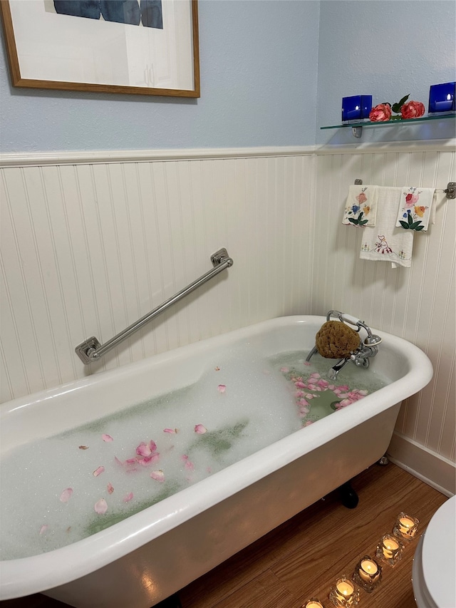 bathroom with hardwood / wood-style floors, toilet, and a bath