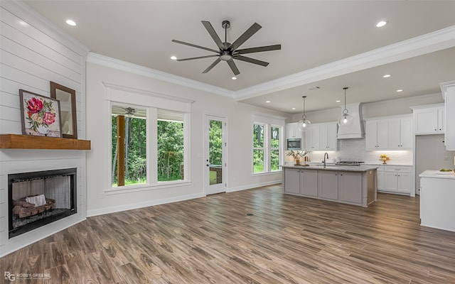 unfurnished living room featuring hardwood / wood-style flooring, ceiling fan, sink, and ornamental molding