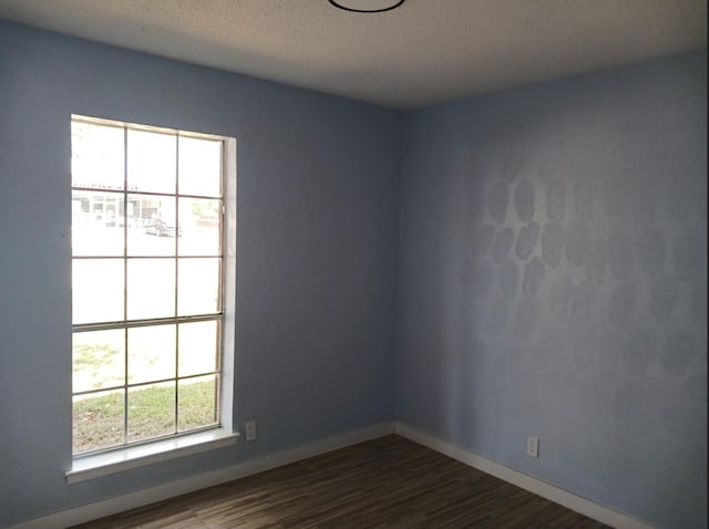 empty room with dark wood-type flooring and a textured ceiling