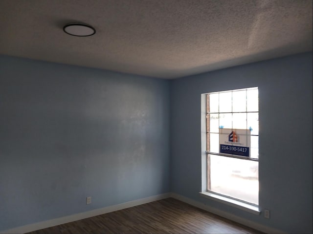 empty room with wood-type flooring and a textured ceiling