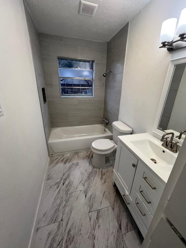 full bathroom with vanity, tiled shower / bath, toilet, and a textured ceiling