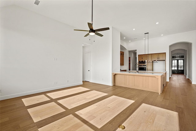 kitchen with light brown cabinetry, light hardwood / wood-style flooring, kitchen peninsula, pendant lighting, and ceiling fan