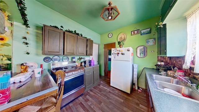 kitchen with gas stove, white refrigerator, dark wood-type flooring, and sink