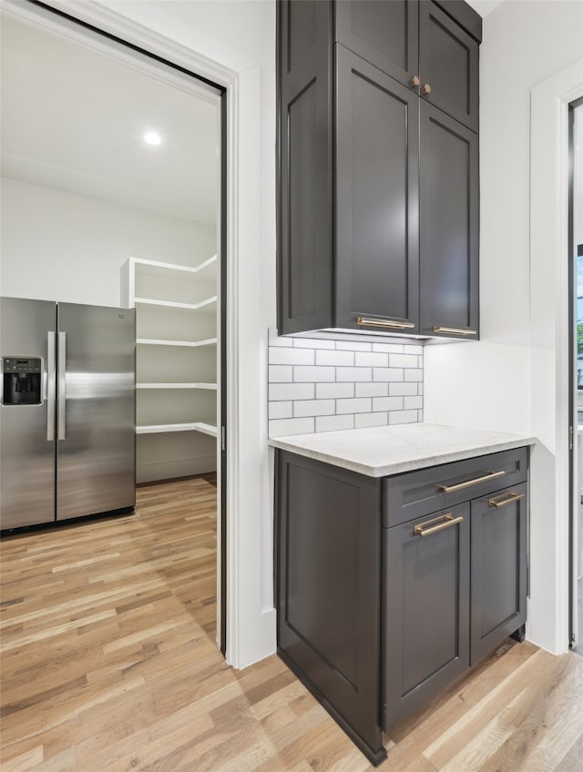 interior space featuring light hardwood / wood-style flooring, backsplash, stainless steel fridge, and gray cabinets