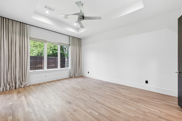 unfurnished room featuring ceiling fan, a raised ceiling, and light hardwood / wood-style floors