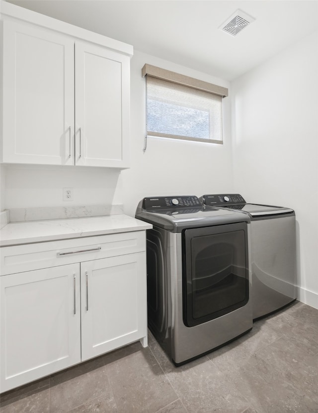 washroom with washer and dryer and cabinets