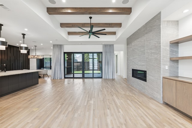 unfurnished living room featuring a tile fireplace, beamed ceiling, tile walls, ceiling fan, and light wood-type flooring