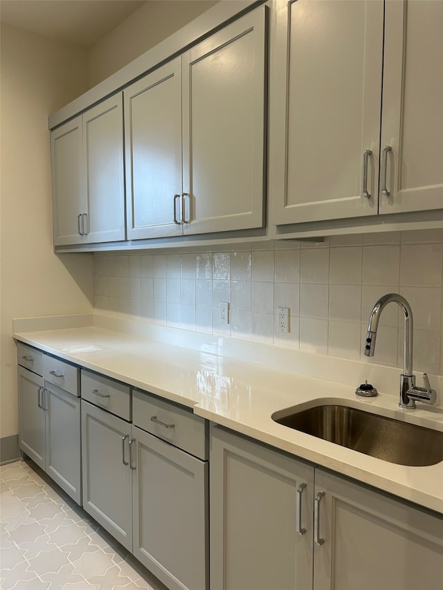 kitchen featuring backsplash, gray cabinetry, and sink