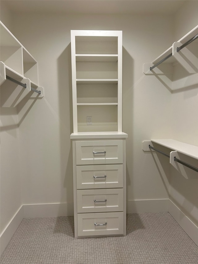 walk in closet with light carpet