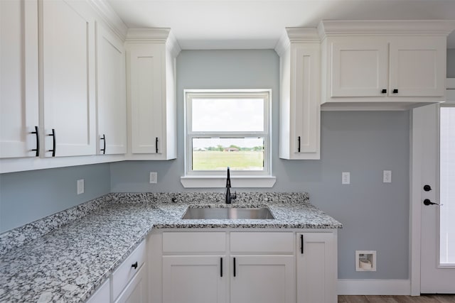 kitchen with sink, white cabinets, and wood-type flooring