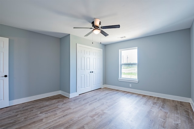 unfurnished bedroom featuring ceiling fan, a closet, and light hardwood / wood-style flooring