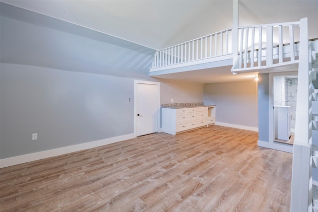 unfurnished living room with high vaulted ceiling and light hardwood / wood-style floors