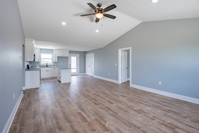 unfurnished living room featuring vaulted ceiling, light hardwood / wood-style flooring, ceiling fan, and sink