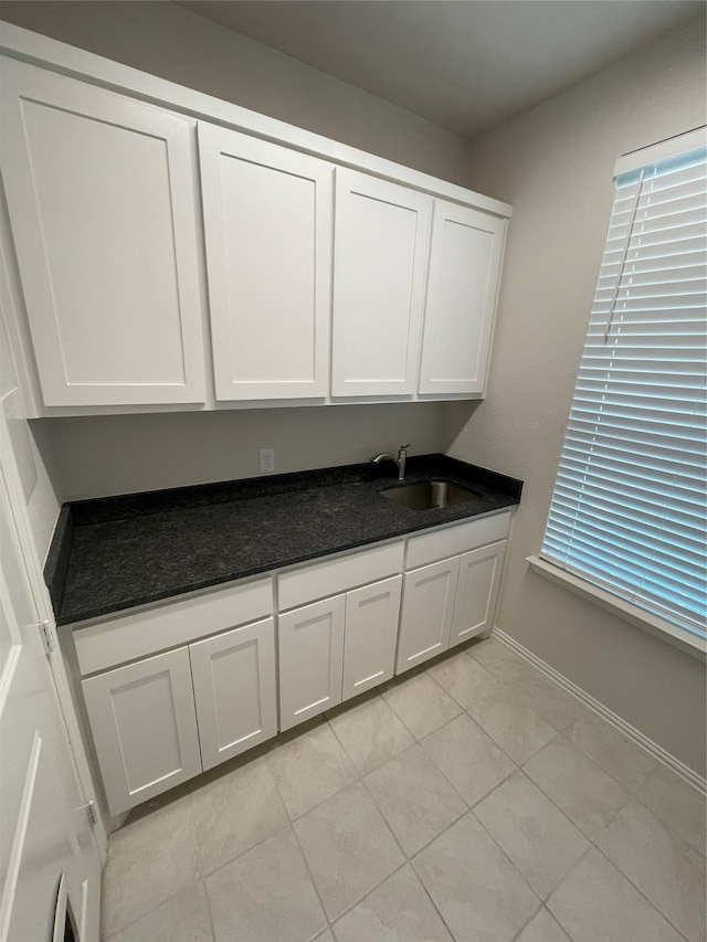 kitchen featuring sink, light tile patterned flooring, and white cabinets