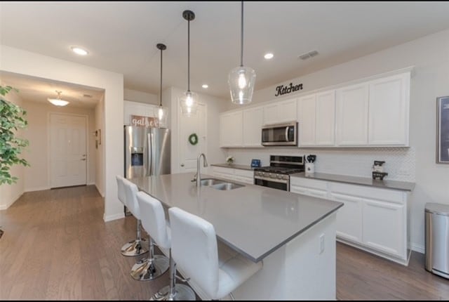 kitchen featuring dark wood-type flooring, a kitchen island with sink, sink, and stainless steel appliances