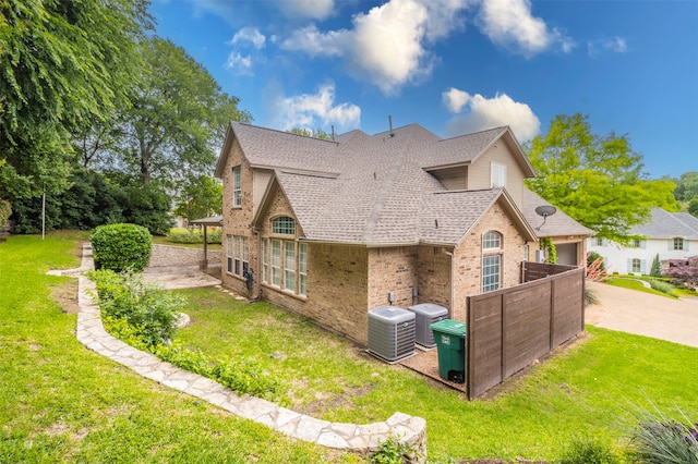 rear view of property featuring a yard and central air condition unit