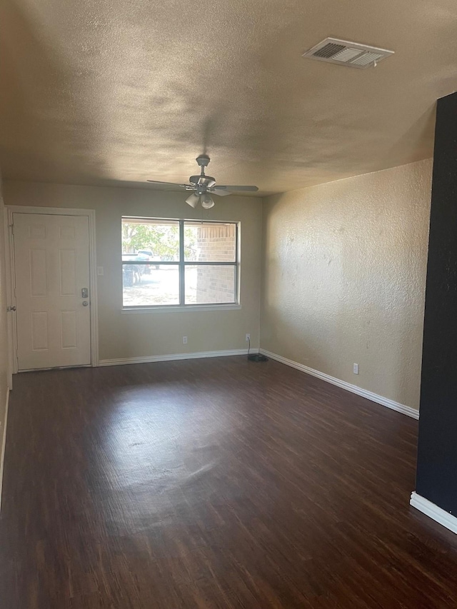 empty room with a textured ceiling, ceiling fan, and dark wood-type flooring