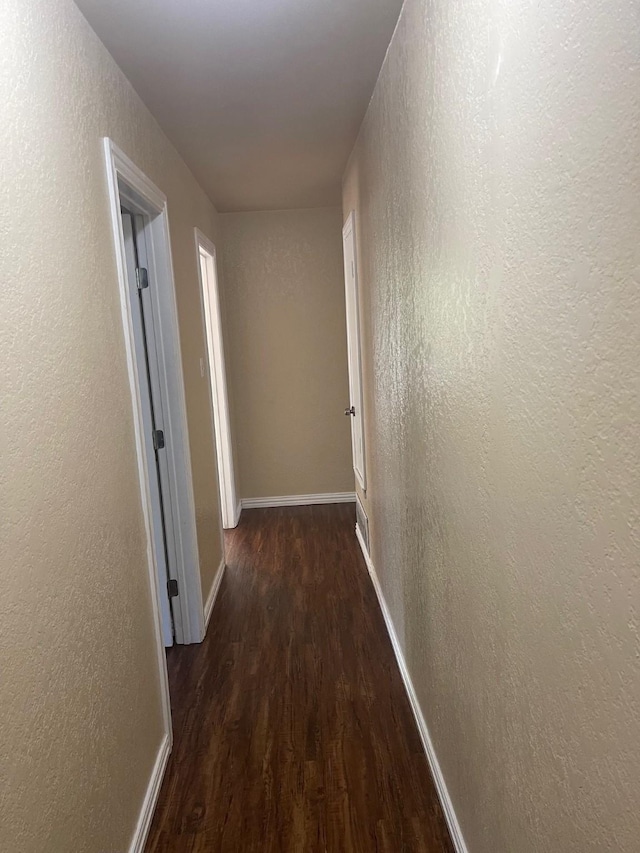 hallway with dark hardwood / wood-style flooring