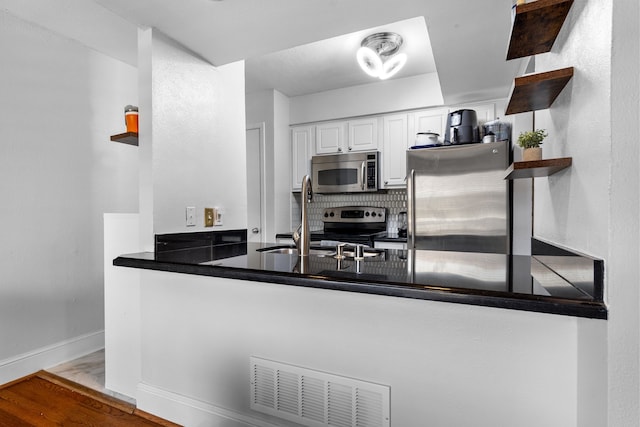 kitchen with sink, stainless steel appliances, decorative backsplash, white cabinets, and light wood-type flooring