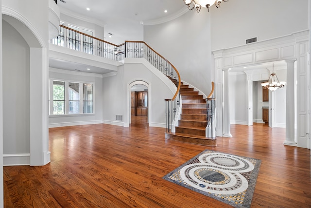 foyer entrance featuring hardwood / wood-style floors, a notable chandelier, a high ceiling, and crown molding