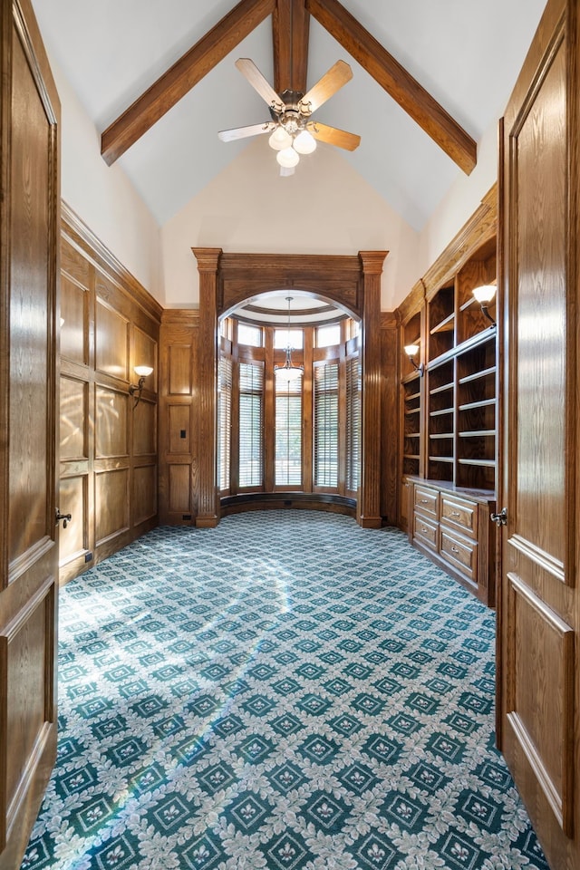 unfurnished living room with high vaulted ceiling, beam ceiling, carpet flooring, and ceiling fan