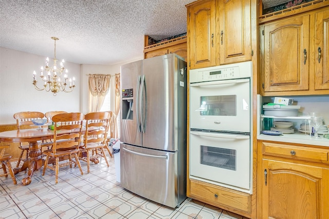 kitchen with white double oven, a textured ceiling, stainless steel fridge with ice dispenser, pendant lighting, and an inviting chandelier