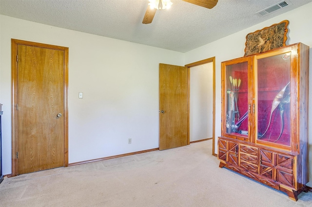 empty room with a textured ceiling, carpet floors, and ceiling fan