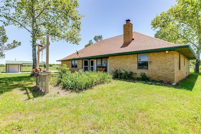 back of house featuring an outdoor structure, a garage, and a lawn