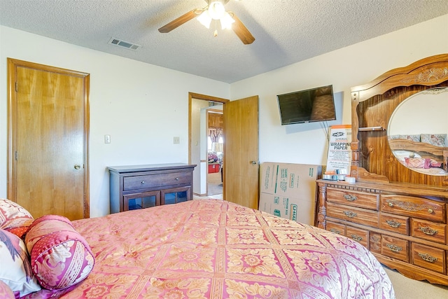 bedroom with ceiling fan, carpet floors, and a textured ceiling