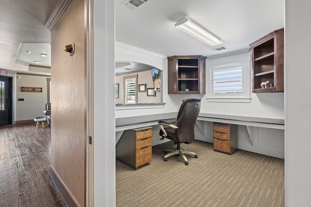 carpeted home office featuring built in desk, ornamental molding, and a tray ceiling