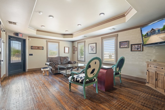 living room featuring dark wood-type flooring, a tray ceiling, and crown molding