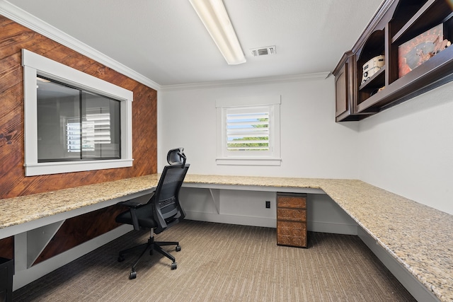 carpeted home office featuring wooden walls, built in desk, and crown molding