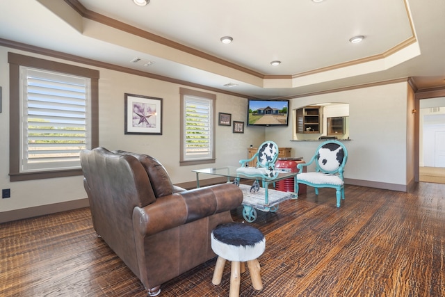 living room featuring a tray ceiling, hardwood / wood-style flooring, ornamental molding, and plenty of natural light