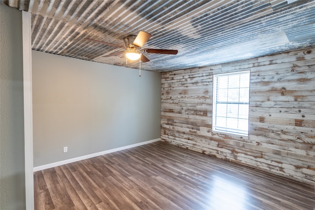 empty room featuring wooden walls, ceiling fan, and hardwood / wood-style flooring