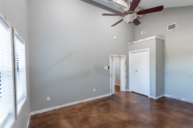 unfurnished bedroom featuring ceiling fan, a closet, and a high ceiling