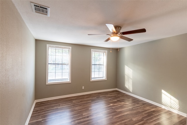 spare room with a textured ceiling, ceiling fan, and dark hardwood / wood-style flooring