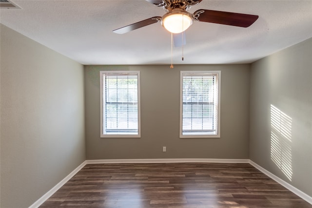 empty room with ceiling fan, a textured ceiling, dark hardwood / wood-style flooring, and a wealth of natural light