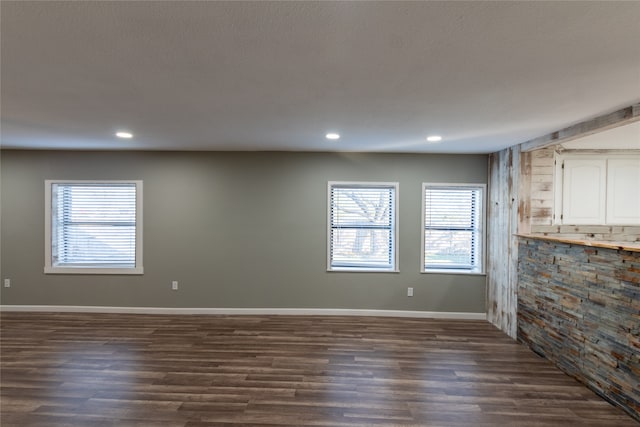 unfurnished living room featuring a textured ceiling and dark wood-type flooring