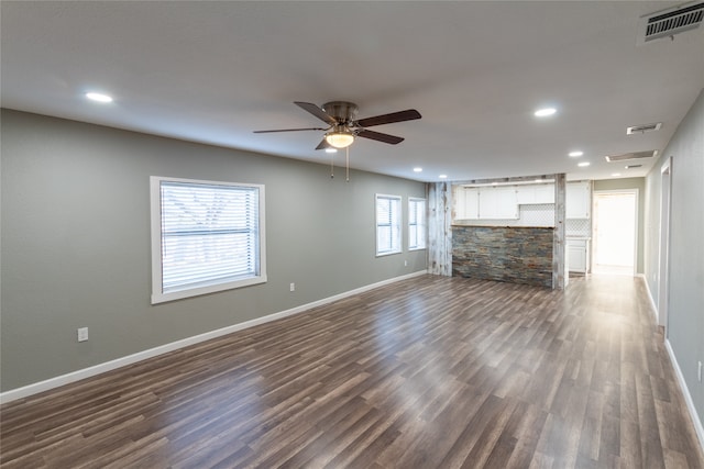 unfurnished living room featuring ceiling fan, plenty of natural light, and dark wood-type flooring