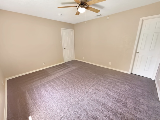 spare room featuring ceiling fan and dark carpet